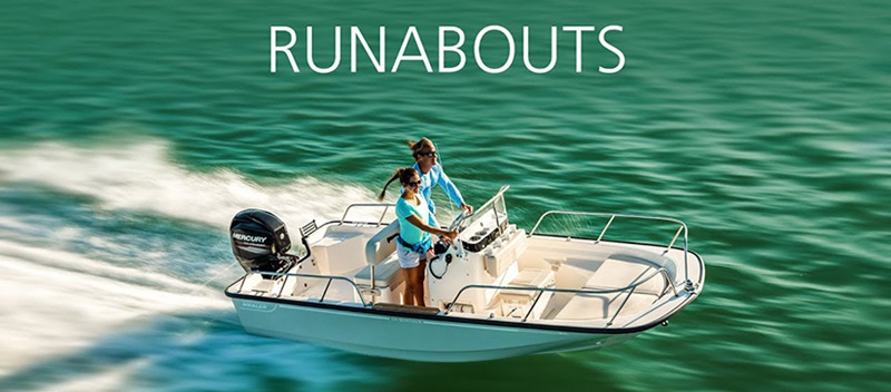 RUNABOUTS - Runabout Boat cutting through water as two people stand at the controls