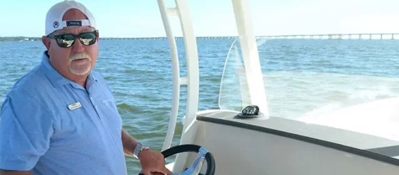 man wearing backwards hat at the helm of a boat