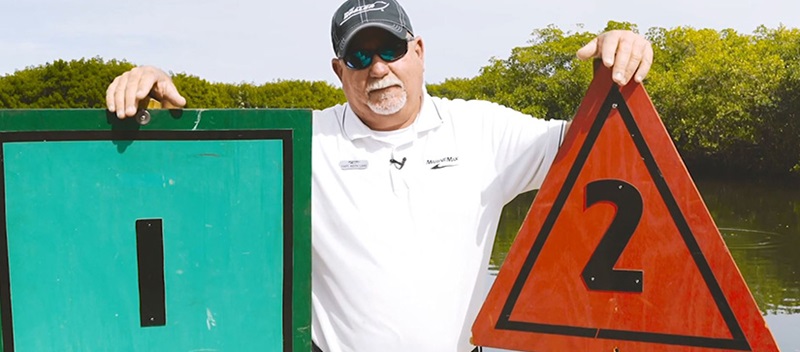 A man standing by two channel markers