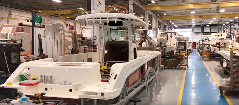 A boat sits in a factory with several tools and materials around it.