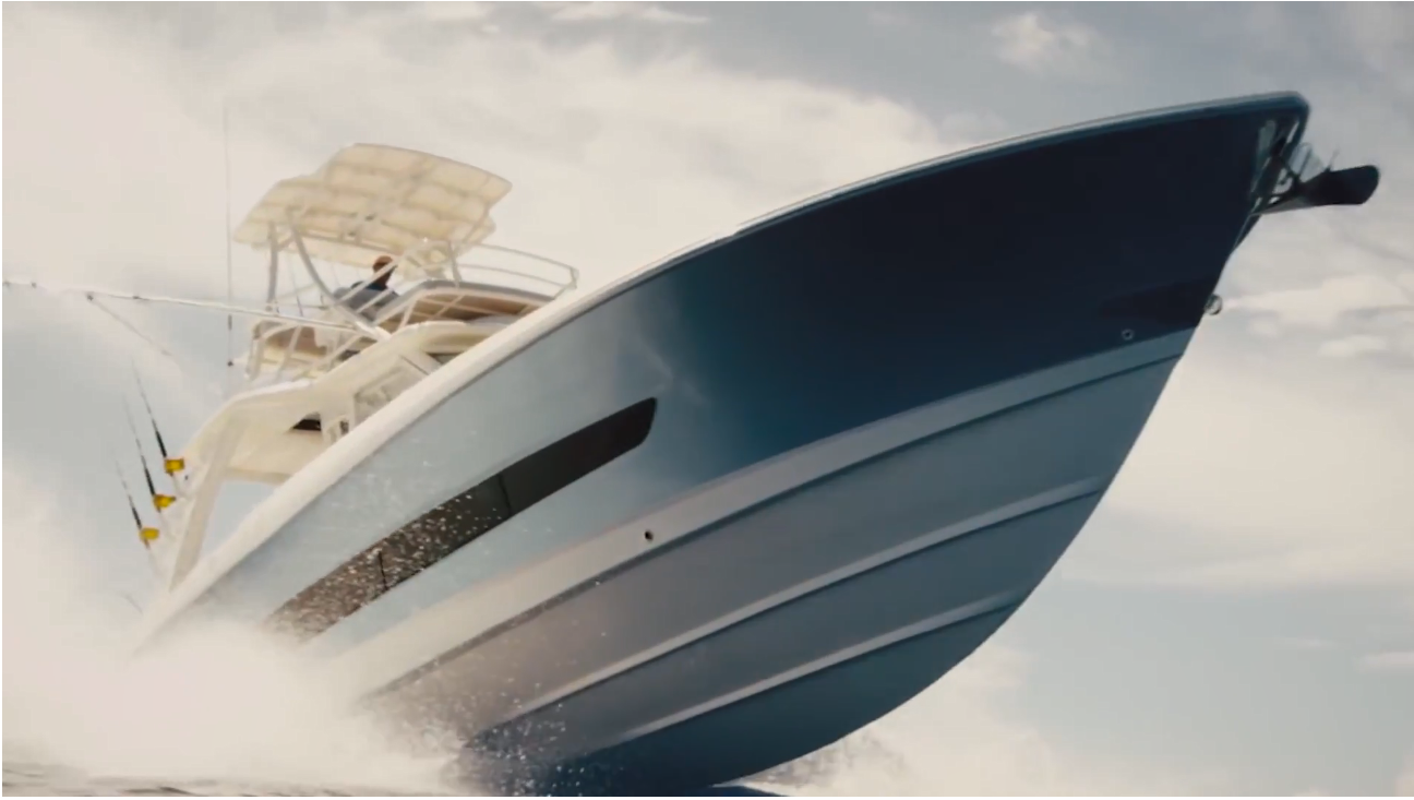 A boat cruises along the water, causing a spray of white foam.