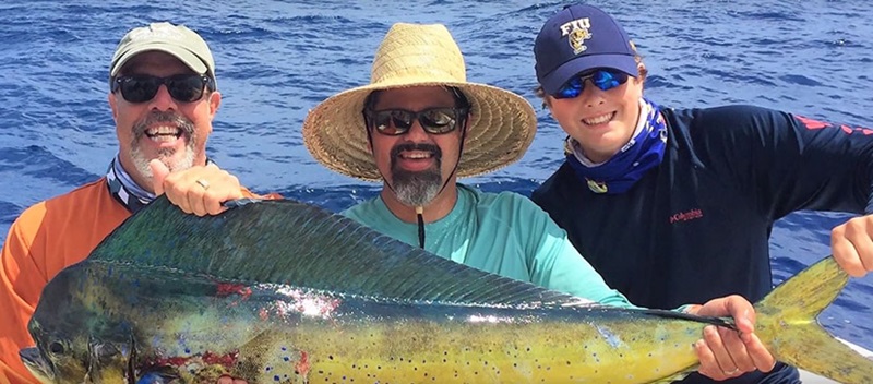 group of three men holding a large fish