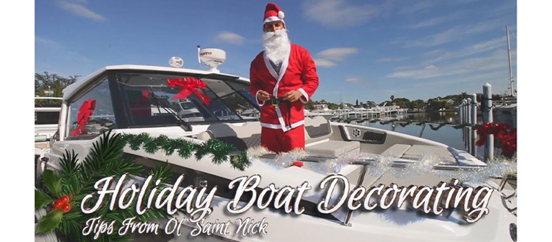 A man in a Santa Claus costume standing aboard a decorated boat