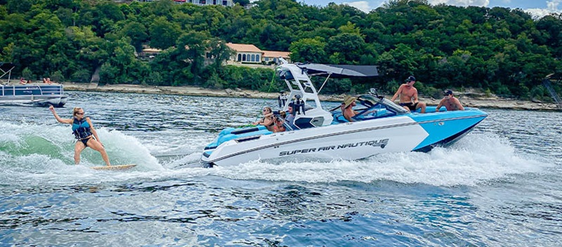 A girl wakesurfing behind a Nautique boat on Lake Austin at the Barrel Boss Wakesurf Competition