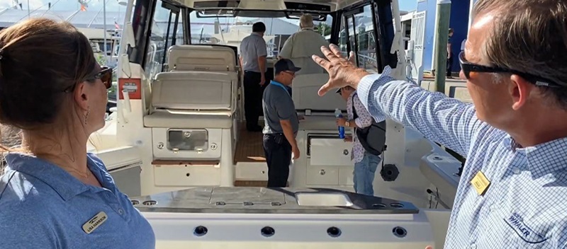 A man and woman in front of the Boston Whaler 405 Conquest, pointing to the stern of the boat