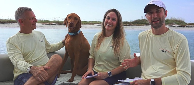Two men and a woman on a boat with a brown dog, smiling at the camera and talking about #MMXPets