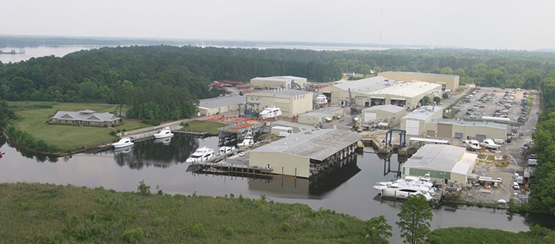 An aerial view of the Hatteras factory, with several warehouses and boats docked in the water nearby
