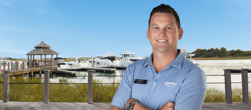 MarineMax employee wearing a blue polo with a dock in the background