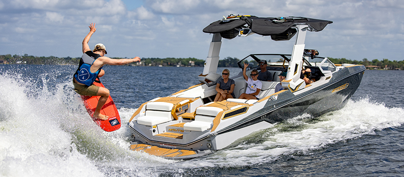 A wakeboarder on the water behind a Nautique