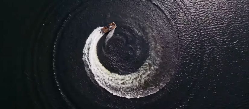 A premier pontoon running in circles making a circular wake on the water