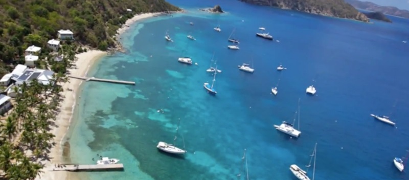 aerial view of crystal clear blue ocean speckled with white yachts