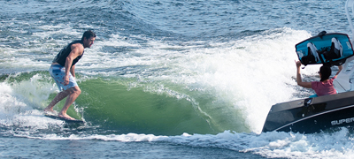 man wake surfing behind speedboat
