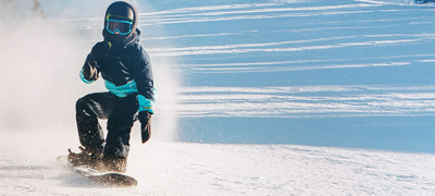 boy snowboarding wearing a helmet going fast