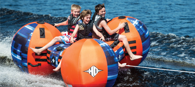 three kids having fun on an inflatable being towed through the water