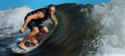 man wakesurfing on a huge nautique paragon g23 wave under blue sky