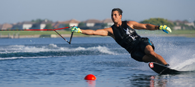 young man slalom skiing around buoys on a private lake