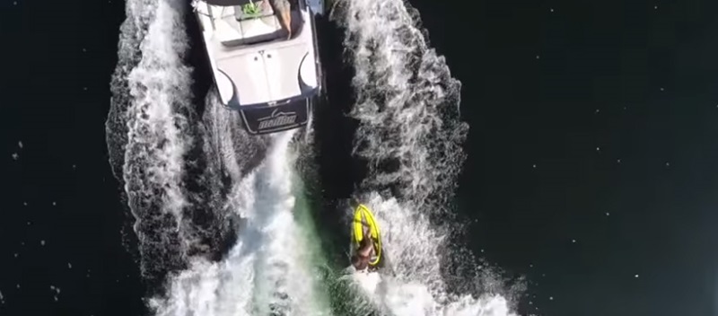 Overhead view of boat in water pulling wakeboarder