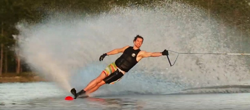 Man being pulled on water skiis, using one arm