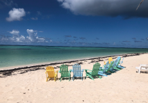 view of a beach in british virgin islands with colorful adirondack chairs