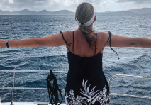 woman standing on a yacht with her arms spread looking out to the ocean