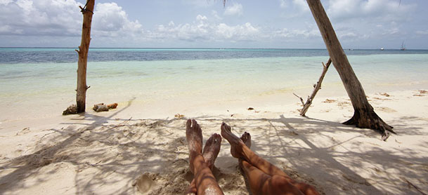 couple laying on beach with only legs showing and water in the background