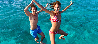 Couple jumping into water with excited faces
