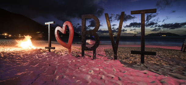 I love BVI sign on beach with bonfire on the side