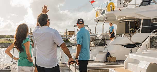 Crew welcoming a couple aboard a catamaran 