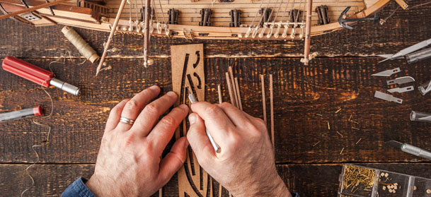 Man collects the vehicle model on the wooden table horizontal