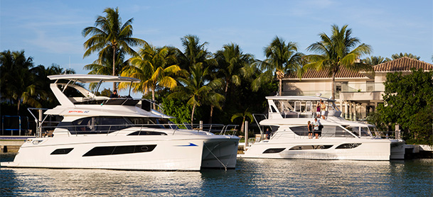 MarineMax 443 and 484 power catamarans in water next to house