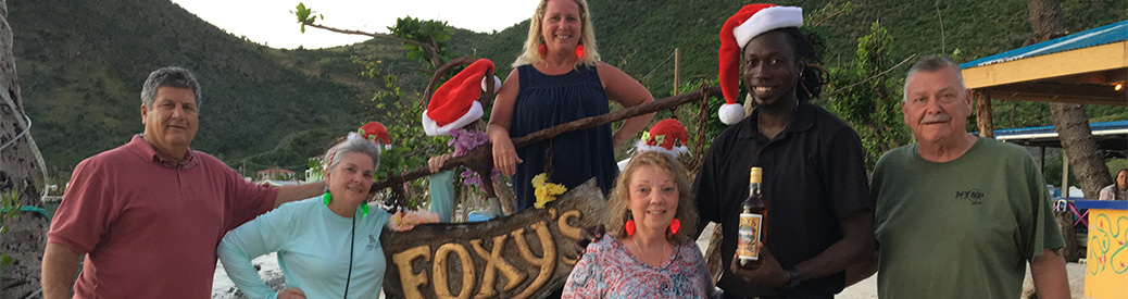 Group of friends standing with the Foxy's sign and wearing Santa hats