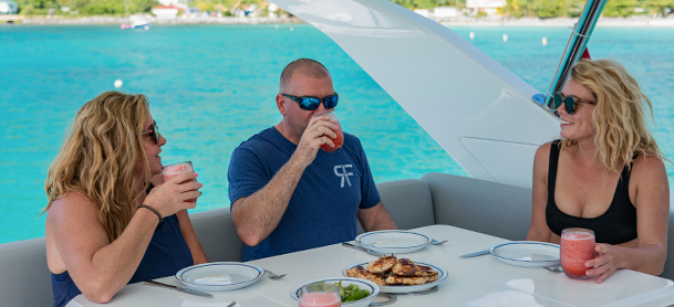 Three people sitting around table with drinks on a MarineMax Charter boat