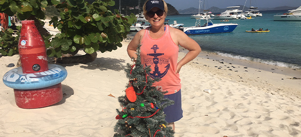 A woman on a beach in front of a Christmas tree