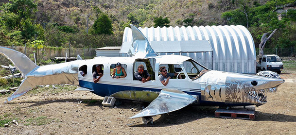 A deconstructed airplane made to look like a shark, resting on a beach in the British Virgin Islands