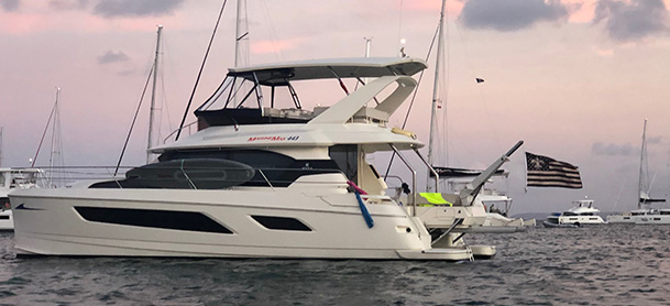 An Aquila Power Catamaran in the water with the sun setting behind it