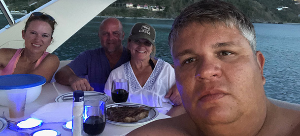 A selfie of a man on a boat with another man and two women, seated at the table on an Aquila power catamaran