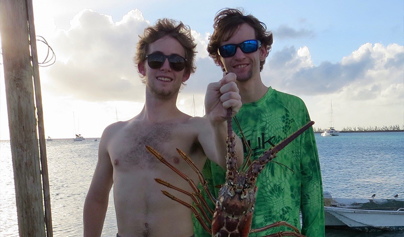 two men standing together and one is holding an anegada lobster
