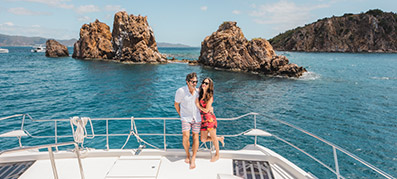 Couple on a yacht with an island behind them