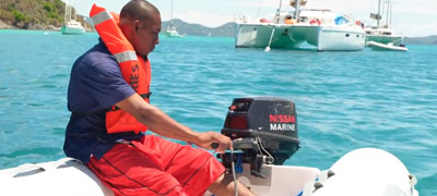 Man in life jacket powering dinghy boat engine