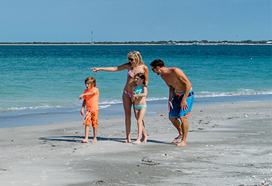 family walking on beach with blue water