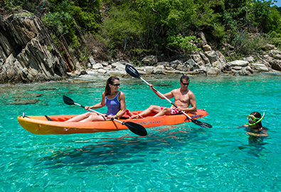 A couple kayaking next to a girl snorkeling