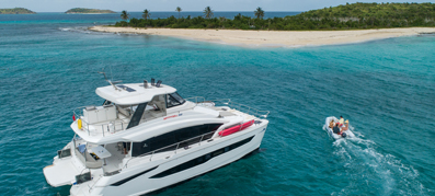 MarineMax Boat driving towards an island with dinghy next to it