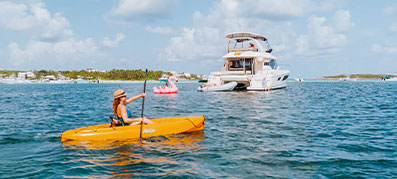 Woman kayaking in front of MarineMax charter