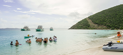 group of people in the water and on the beach with MarineMax charters in the distance