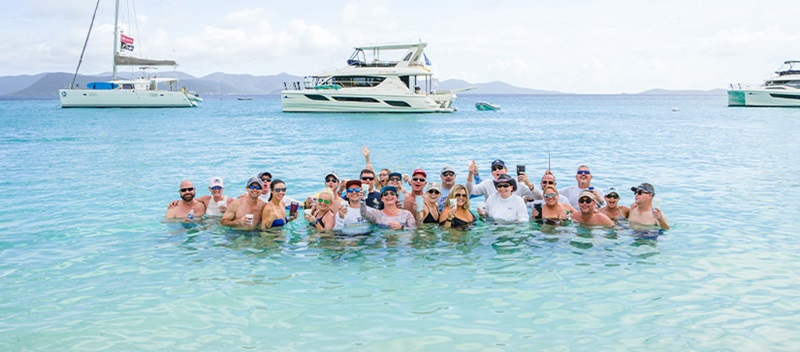 A group of people in the water in front of an Aquila power catamaran in the BVI