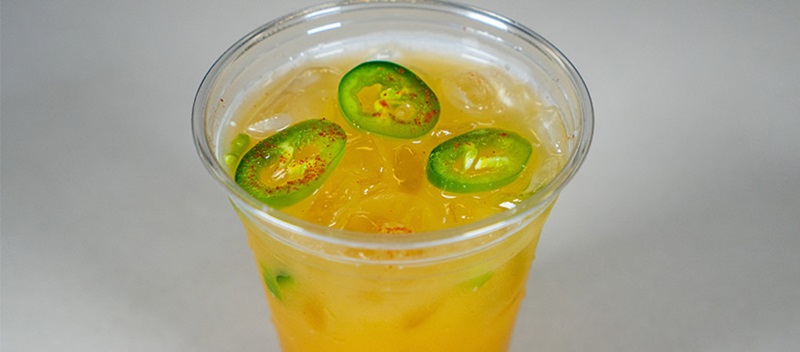 orange drink in a cup with jalapeno slices