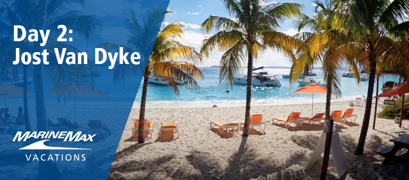 View of beachfront of Jost Van Dyke with palm trees and boats in the water
