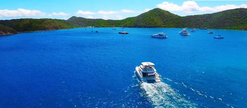 boat driving in wide open deep blue water with island in the distance