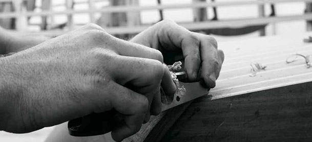 Black and white photo of hands holding a tool and working on a piece of wood