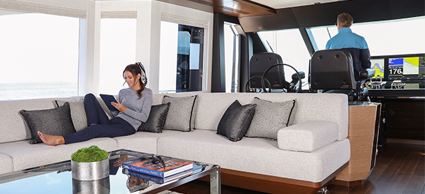 Woman sitting on a couch inside a yacht with man at the helm